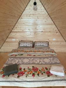 a bed in a room with a wooden wall at Conacul lui Patrick in Poenari