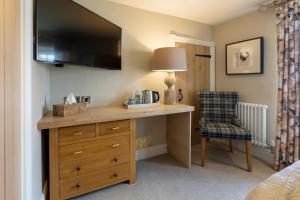 a bedroom with a desk with a television on a wall at The Fox and Hounds Country Inn in Pickering