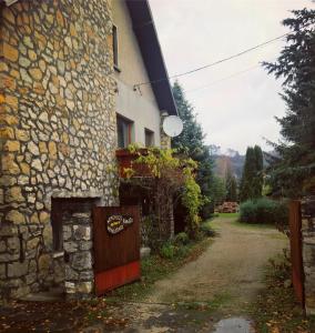 a stone house with a gate next to a dirt road at Bakonyi Kemencésház in Bakonybél