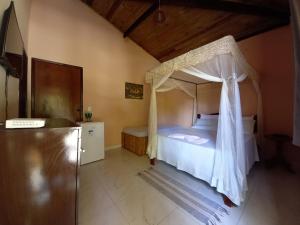 a bedroom with a bed with a canopy at Recanto Verde - Praia de Santo Antônio in Diogo