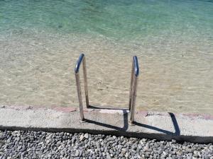 une chaise de plage assise dans le sable près de l'eau dans l'établissement Olea, à Tivat