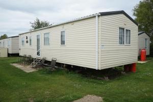 a large white mobile home with chairs in a yard at The Pet Friendly Pad in Hunstanton