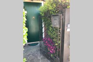 uma entrada para uma porta verde com flores cor-de-rosa em Barchessa Ca’ Leon sul naviglio del Brenta em Mira