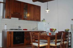 una cocina con armarios de madera y una mesa con sillas. en Casa Vacanze La Guardia, en Tortorella