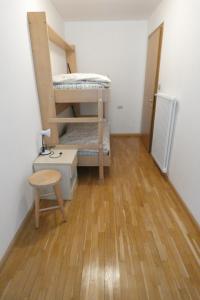 a room with two bunk beds and a wooden floor at Casa Al Mesdì in Pozza di Fassa