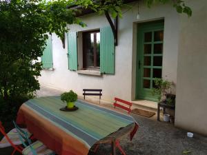 uma mesa e cadeiras em frente a uma casa com janelas verdes em Chambre avec salle de bains privative em Boutiers-Saint-Trojan