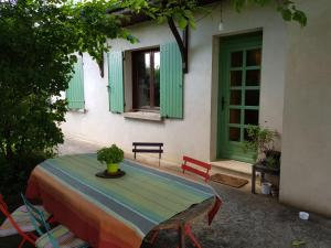 a table and chairs in front of a house with green windows at Chambre avec salle de bains privative in Boutiers-Saint-Trojan
