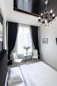 リヴィウにあるLEOGRAND Apartments on Udatnogo 4-2のベッドルーム1室(ベッド1台、テーブル、シャンデリア付)