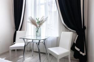 リヴィウにあるLEOGRAND Apartments on Udatnogo 4-2の白い椅子2脚付きのガラステーブル、花瓶