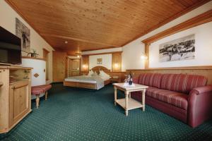 Habitación de hotel con sofá y cama en Hotel Hirschen en Silbertal