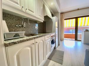 a kitchen with white cabinets and a sink at Apartamentos Neptuno in Platja  d'Aro