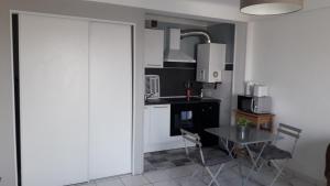 a small kitchen with a table and a sink at Residence d'Anjou - Grand studio avec balcon et parking privatif in Perpignan