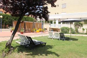 a group of chairs sitting in the grass under a tree at Estrella de Mar Youth Hostel in Calella