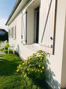 a white house with a window and a bush with yellow flowers at La Longère à la Mer 6 pers 3 chambres grand jardin clôt a Fort-Mahon-Plage in Fort-Mahon-Plage