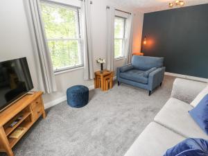 sala de estar con sofá, TV y silla en Victoria House, en Holmfirth
