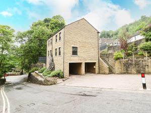 un antiguo edificio de ladrillo con un garaje en una calle en Victoria House, en Holmfirth