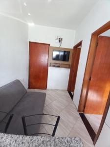 a living room with a couch and a tv on a wall at Apartamento avenida 07 com ar condicionado in São Thomé das Letras