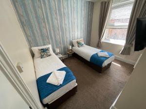 a small room with two beds and a television at The Wash & Tope in Hunstanton
