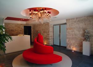 a red chair in a room with a chandelier at El Homs Palace Hotel in Comiso