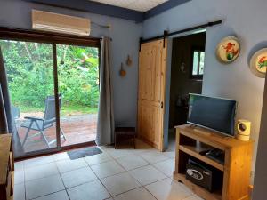 a living room with a television and a door to a patio at Casa Oceana Bed & Breakfast in Bocas del Toro