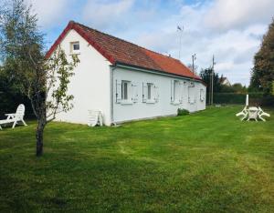 a white house with a green yard with a bench at La Longère à la Mer 6 pers 3 chambres grand jardin clôt a Fort-Mahon-Plage in Fort-Mahon-Plage