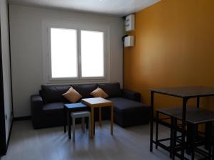 ein Wohnzimmer mit einem Sofa, Tischen und einem Fenster in der Unterkunft La dépendance du vieux tilleul- Gorges Tarn et Jonte in Meyrueis