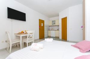 a white room with a table and a tv on the wall at House Kovacevic in Makarska