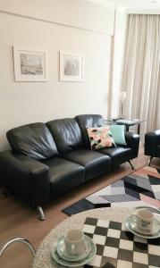 a black leather couch in a living room with a table at Flat Centro Campinas - L'Hirondelle 125 in Campinas