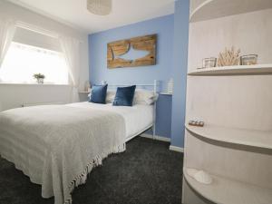 a bedroom with blue walls and a bed with blue pillows at Estuary View in Newquay