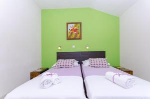 two beds in a bedroom with green walls at House Kovacevic in Makarska