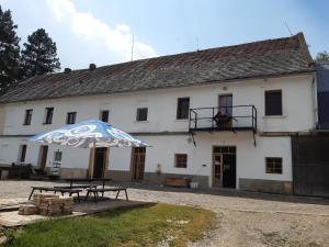 a white building with an umbrella in front of it at Stáj Zakšín - špejchar in Dubá