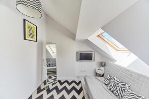 sypialnia na poddaszu z łóżkiem i telewizorem w obiekcie Porta Mare Apartments LuxView III w Dziwnówku
