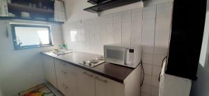 a small kitchen with a microwave on a counter at Shell in Rogoznica +10 photos