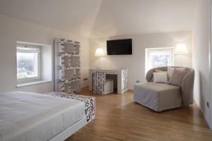 a bedroom with a bed and a chair and a television at Santa Cesarea Residence Luxury Suite - La vetta del Sasso Barisano in Matera