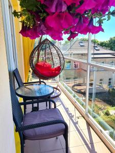 - un balcon avec une table, des chaises et une corbeille de fleurs dans l'établissement Justinos Vila, à Palanga