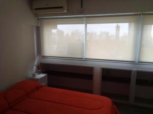 a room with a red couch in front of a window at Depto Plaza Moreno in La Plata