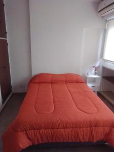 a bed with an orange comforter in a room at Depto Plaza Moreno in La Plata