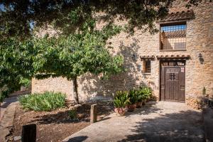 un edificio de piedra con una puerta de madera y algunas plantas en Casa rural dels Hospitalaris, en Traiguera