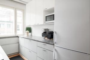 uma cozinha com armários brancos e um frigorífico em City Star em Jyväskylä