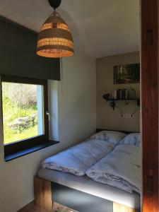 uma cama num quarto com uma janela e um candeeiro em Ferienwohnung Wegespinne em Zwota