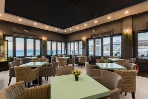 un restaurante con mesas, sillas y ventanas en Klimis Hotel, en Spetses