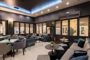 a restaurant with couches and tables and windows at Klimis Hotel in Spetses
