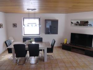 a dining room with a table and chairs and a television at A25 FeWo 180qm mit 5 Schlafzimmer, 2 Badezimmer für bis zu 8 Personen in Abstatt