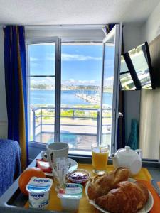 a table with a plate of food and a window with a view at Couett'Hôtel Brest Port de plaisance, Les pieds dans l'eau in Brest