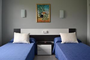 a room with two beds and a picture on the wall at Dukes Habitaciones in Bascuas