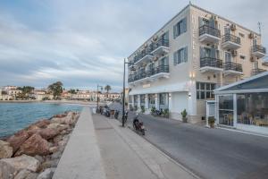 un grand bâtiment blanc avec des motos garées à côté de l'eau dans l'établissement Klimis Hotel, à Spetses