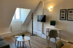 Una sala de estar con un sofá y un televisor. en Le Cheval Bixio, en Beaune