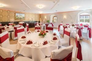 a banquet hall with white tables and red chairs at Schlosshotel Klaffenbach in Chemnitz