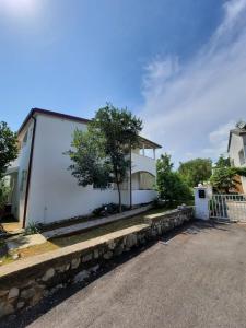 a white house with a tree next to a street at Apartmani Darko in Kornić
