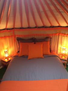 1 cama en una tienda de campaña con 2 lámparas en las mesas en Yourte mongole, en Huriel